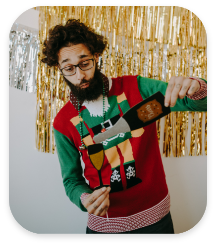 Man wearing ugly christmas sweater holding paper glass and bottle