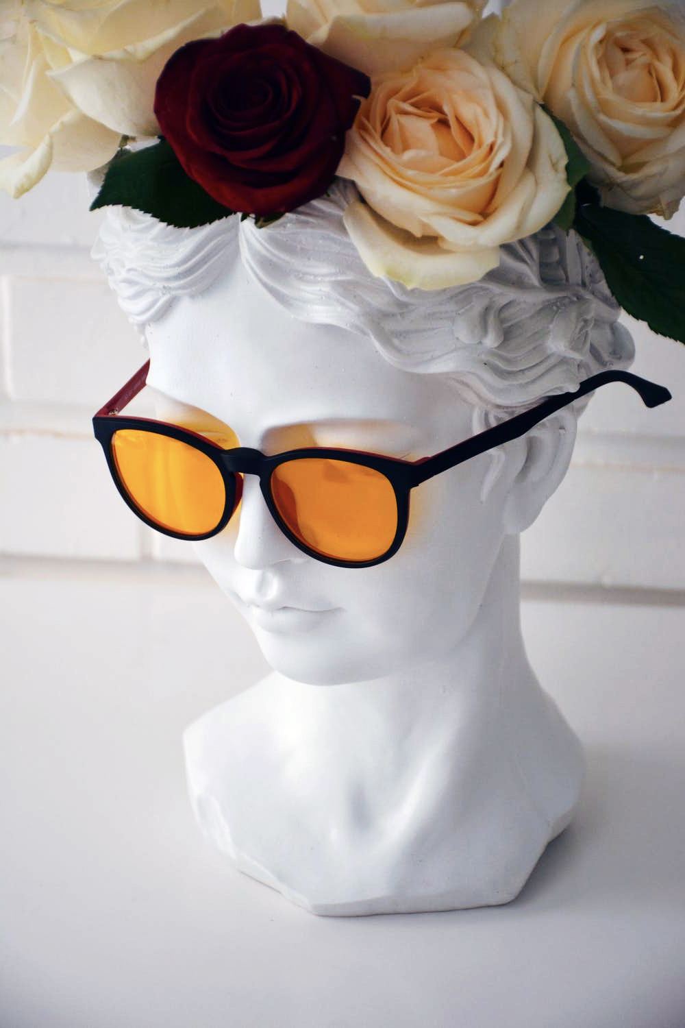 A portrait bust in a flower wreath and sunglasses